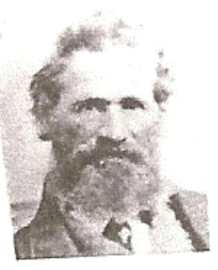 Black and white portrait of an older man with a thick beard and mustache, wearing a jacket and facing the camera.