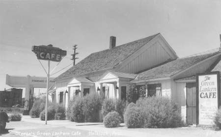 Black and white photo of a roadside diner with a sign reading "Green Lantern Cafe" and vintage gas station equipment visible on the left.