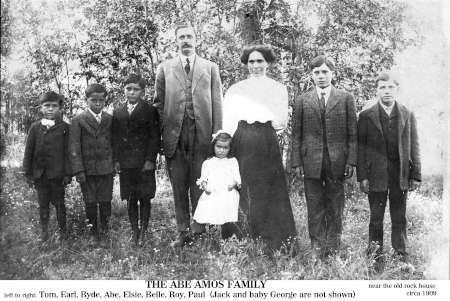 Black-and-white photo of the Abe Amos family standing outdoors in a row, with seven children and two adults, dressed in early 20th-century clothing.