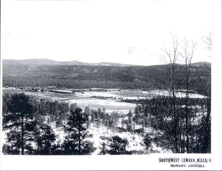 Black and white photo of a lumber mill complex surrounded by forest and mountains near McNary, Arizona; labeled “Southwest Lumber Mills, Inc.” in the corner.