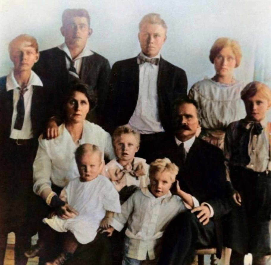 A vintage family portrait showing two adults and eight children, all dressed in early 20th-century clothing, posed and looking at the camera.
