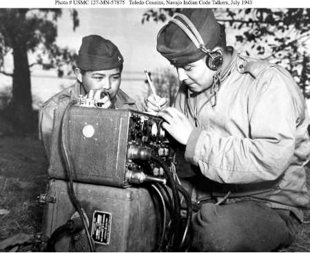 Two Navajo Code Talkers operate a radio communication device outdoors while wearing military uniforms and headsets, July 1943.